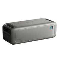 A portable rectangular gray Anker Bluetooth speaker with a mesh front, power button, dual side ports, and textured finish—perfect for off-grid or emergency audio use.