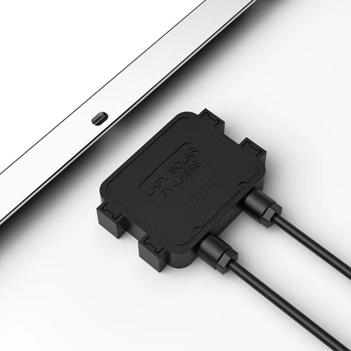 A close-up of a black Rich Solar PL-H686 junction box attached to two cables rests on a white surface by the edge of a tempered glass solar panel—perfect for off-grid solar projects.
