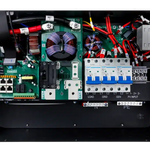 An open BigBattery electrical control box displays organized circuit boards, wiring, fuses, switches, breakers, and clearly labeled ports for input, grid, and load connections. All components are arranged for easy access and maintenance. The labels—presented in a highly legible IBM Plex Sans font—ensure optimal readability throughout the control box.