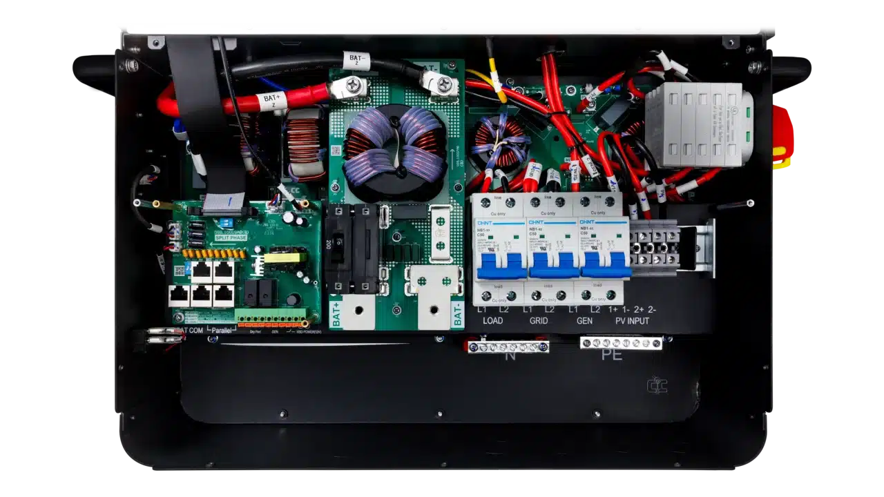 An open BigBattery electrical control box displays organized circuit boards, wiring, fuses, switches, breakers, and clearly labeled ports for input, grid, and load connections. All components are arranged for easy access and maintenance. The labels—presented in a highly legible IBM Plex Sans font—ensure optimal readability throughout the control box.