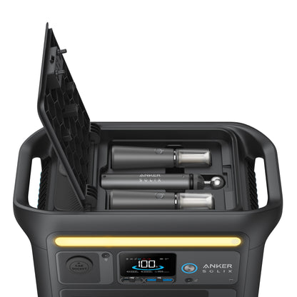 An Anker Solix power station in black with its top open displays two LiFePO4 batteries and charging slots, ideal for powering camping lights. The front panel features multiple ports, settings, and a digital display.