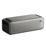 A portable rectangular gray Anker Bluetooth speaker with a mesh front, power button, dual side ports, and textured finish—perfect for off-grid or emergency audio use.