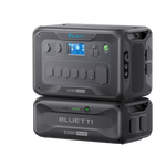 A Bluetti AC300 3000W portable power station with digital controls is stacked on a Bluetti B300K 3072Wh LiFePO₄ battery module. Both black units feature textured panels, visible ports, and advanced UPS protection.