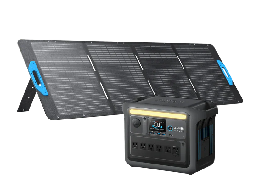A portable solar panel is set up at an angle beside a black Anker SOLIX C1000X Portable Power Station, which features multiple outlets and a front display screen.