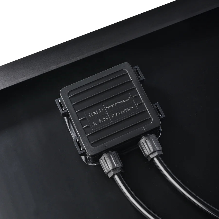 Close-up of a Rich Solar black electrical junction box with two cables attached, mounted on a flat black surface—ideal for off-grid solar trailers or portable solar charging kits. Technical info and symbols are displayed on the box.