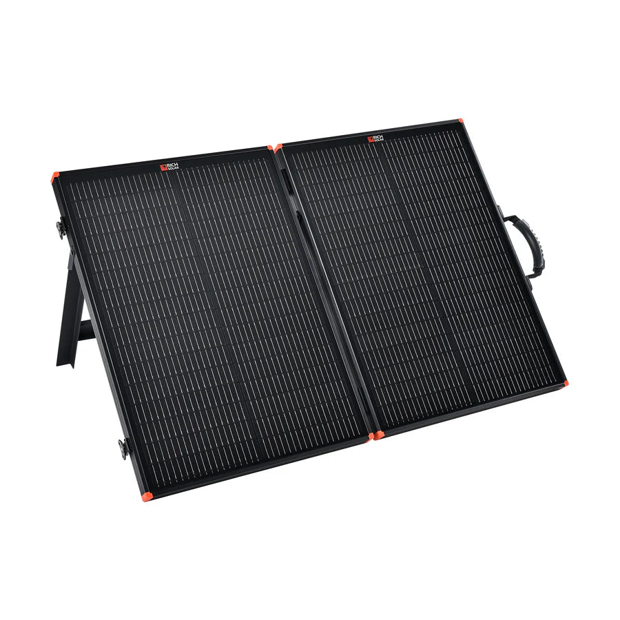The Rich Solar portable solar charging kit features a foldable black panel with orange corners, stand, and carrying handle—ideal for off-grid trailer setups—all shown against a white background.