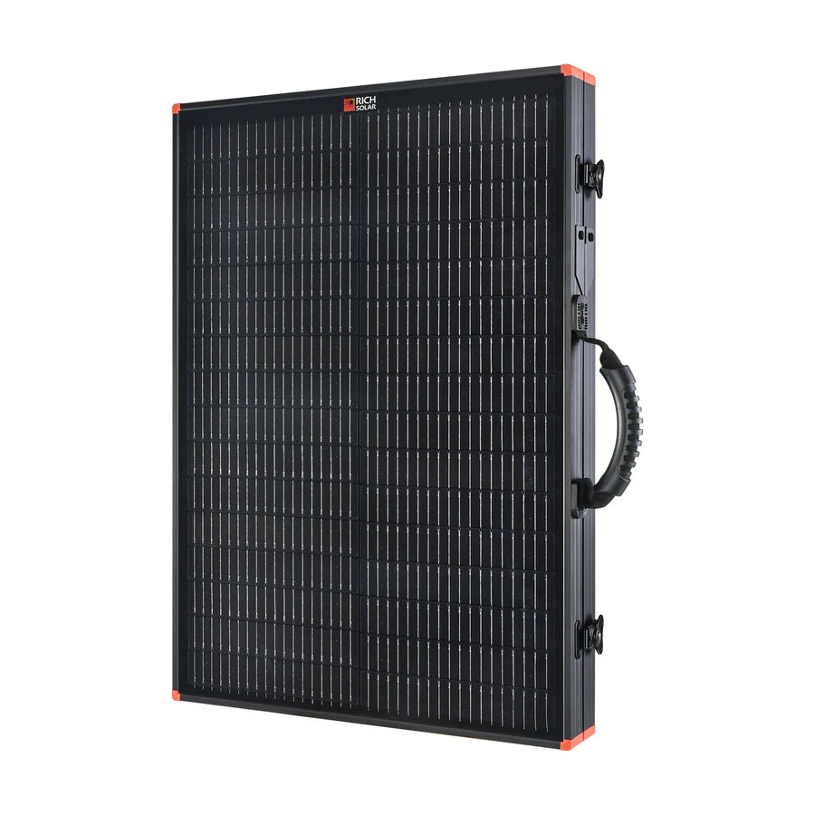 The Rich Solar portable solar charging kit is black and rectangular, featuring a grid of thin white lines, red corner accents, and a curved carrying handle on the right side.