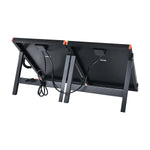 A rear view of two black, rectangular Rich Solar portable solar panels side by side on foldable stands, with visible cables connected to their backs.