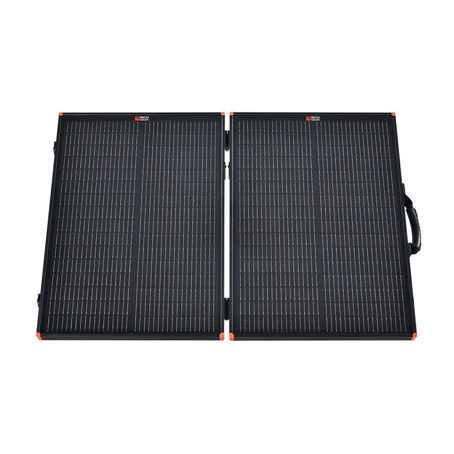 The Rich Solar foldable black portable charging kit features two rectangular solar panels connected by a hinge, a right-edge handle, and red corner accents—perfect for powering an off-grid solar trailer.
