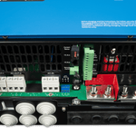 Close-up of the back panel of a blue Victron device showing multiple AC/DC connections, ports, terminal blocks, wiring inputs, clear labels, and a cooling vent.