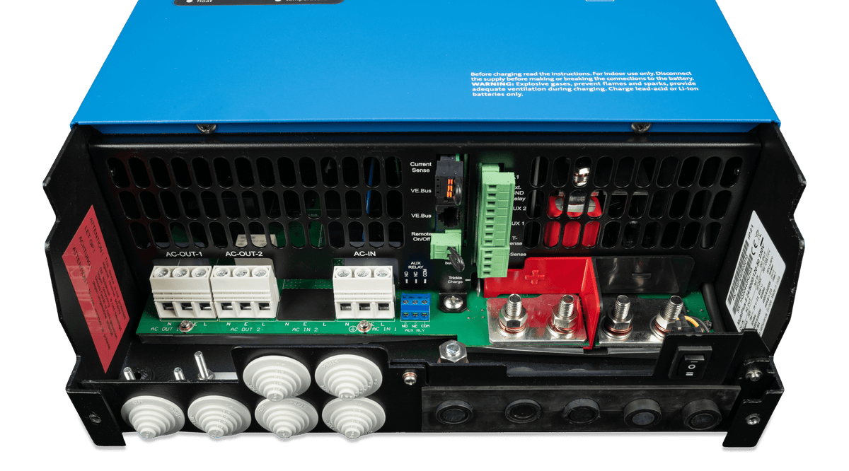 Close-up of the back panel of a blue Victron device showing multiple AC/DC connections, ports, terminal blocks, wiring inputs, clear labels, and a cooling vent.