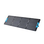 The Anker portable, foldable solar panel features four black rectangular sections, blue handles at both ends, a built-in stand, IP67 waterproof protection, and is shown against a white background.