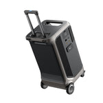 A portable, black and gray Anker Solix F3800 power station with expandable capacity, wheels, telescopic handle, multiple outlets, and side air vents, resembling a compact suitcase.