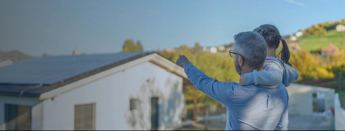 Father and daughter looking at a house with solar panels